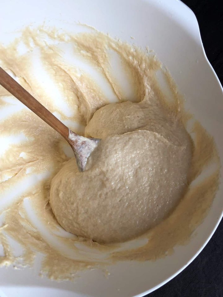 Mixing a yeast cake dough with a wooden spoon.