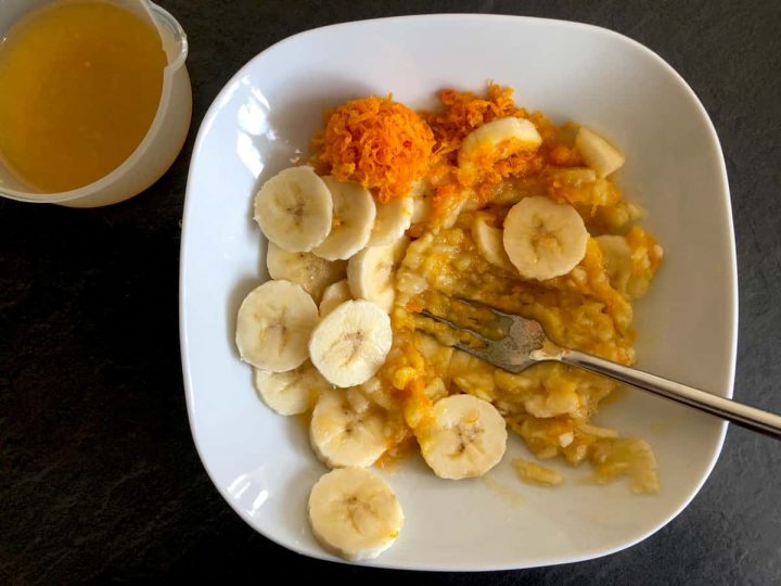 mashing a banana and orange zest with a fork in a bowl