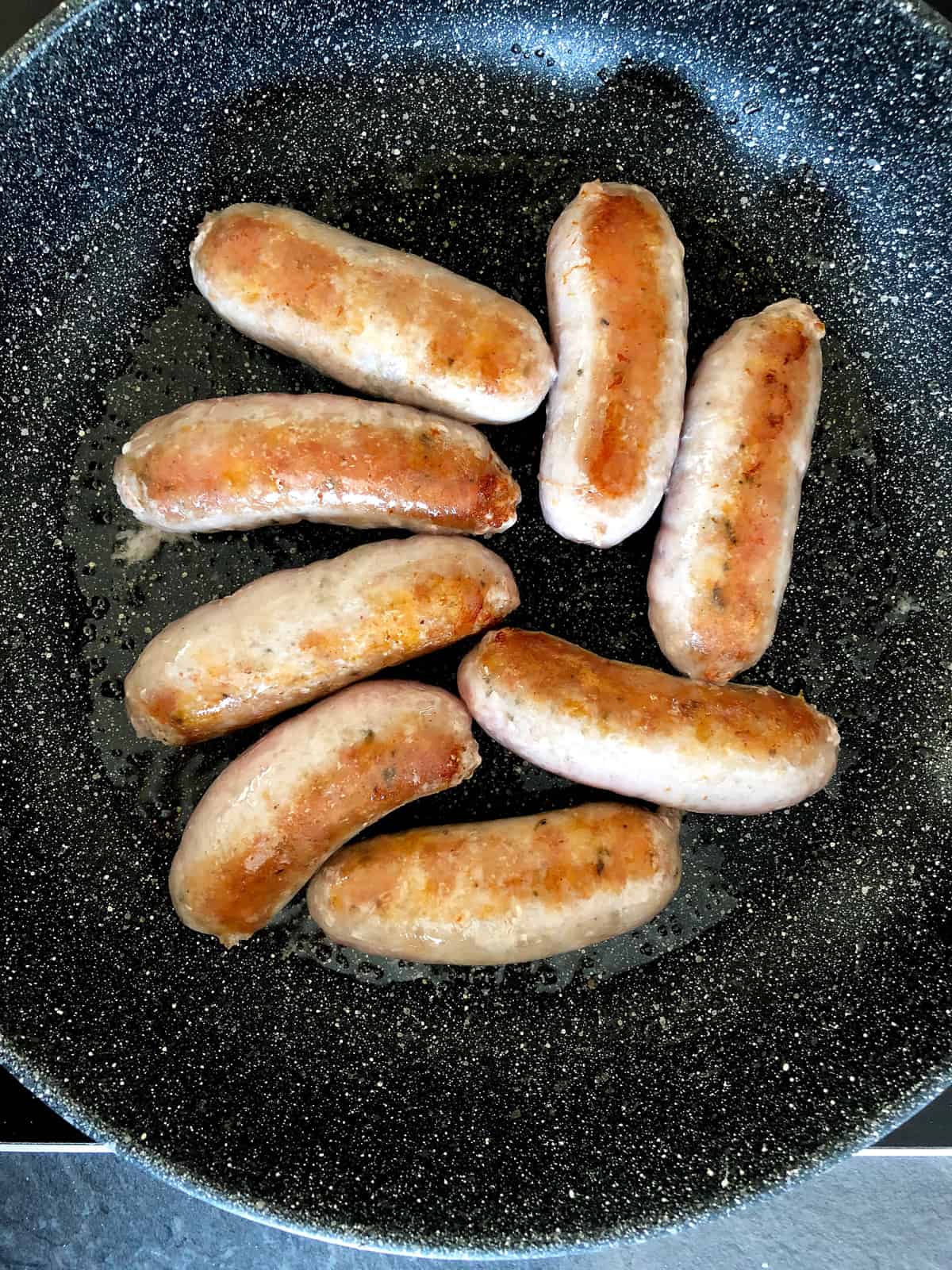 Browning sausages in a pan