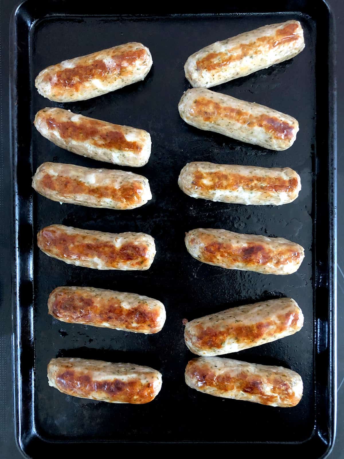 Oven-grilled sausages on a baking tray