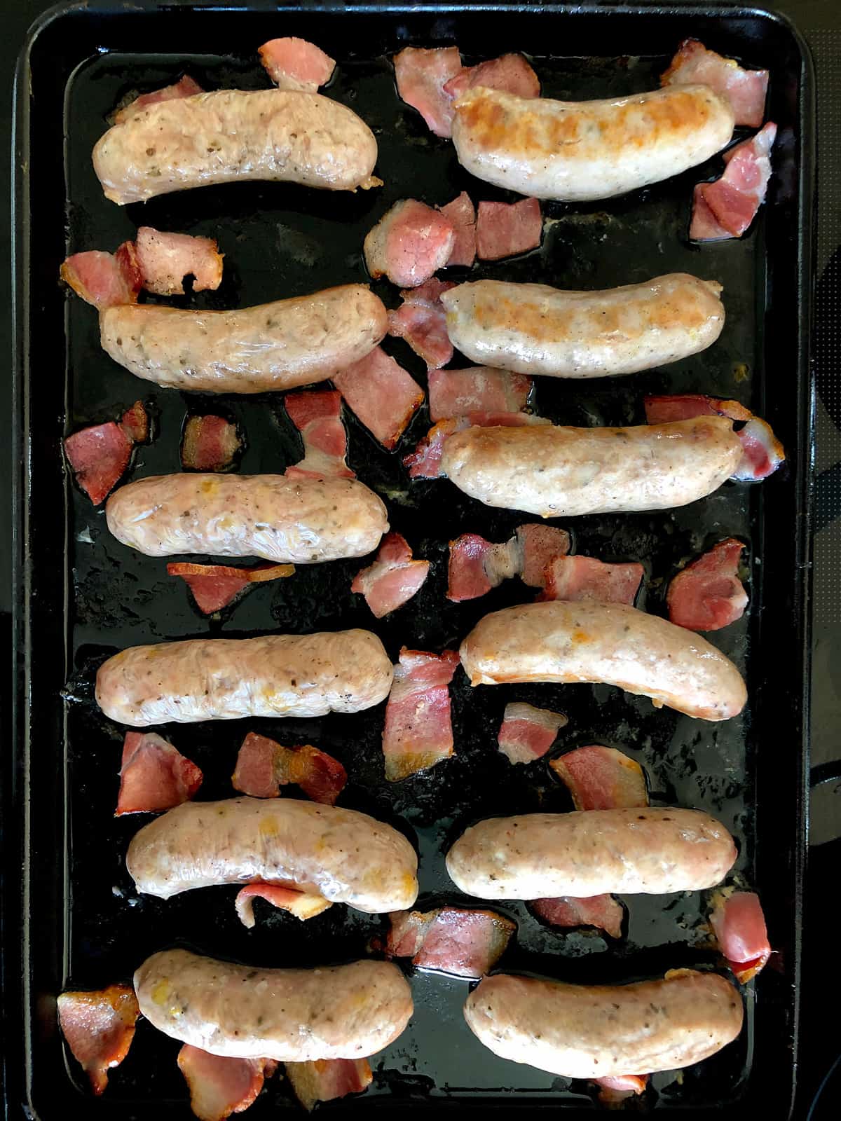 Sausages and pieces of bacon on a tray
