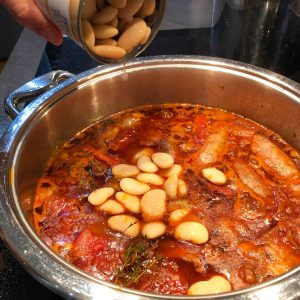 tipping butter beans into the casserole