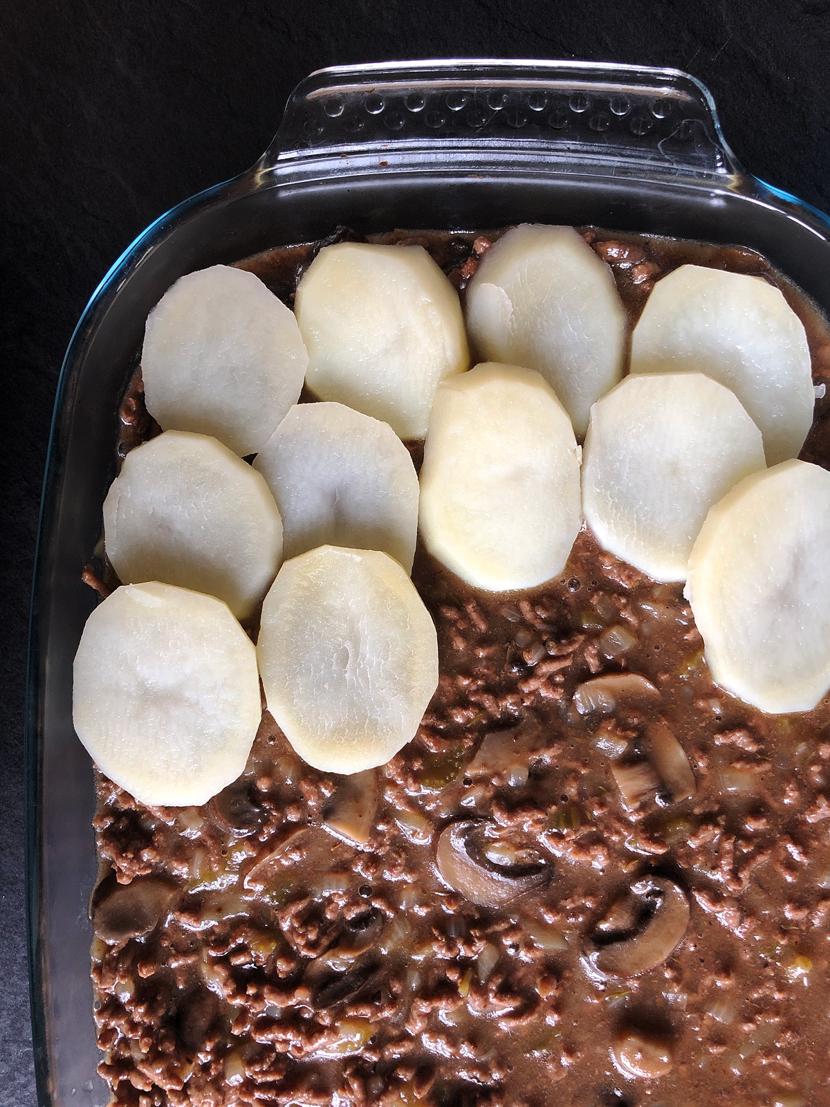 sliced potatoes on top of a cottage pie filling