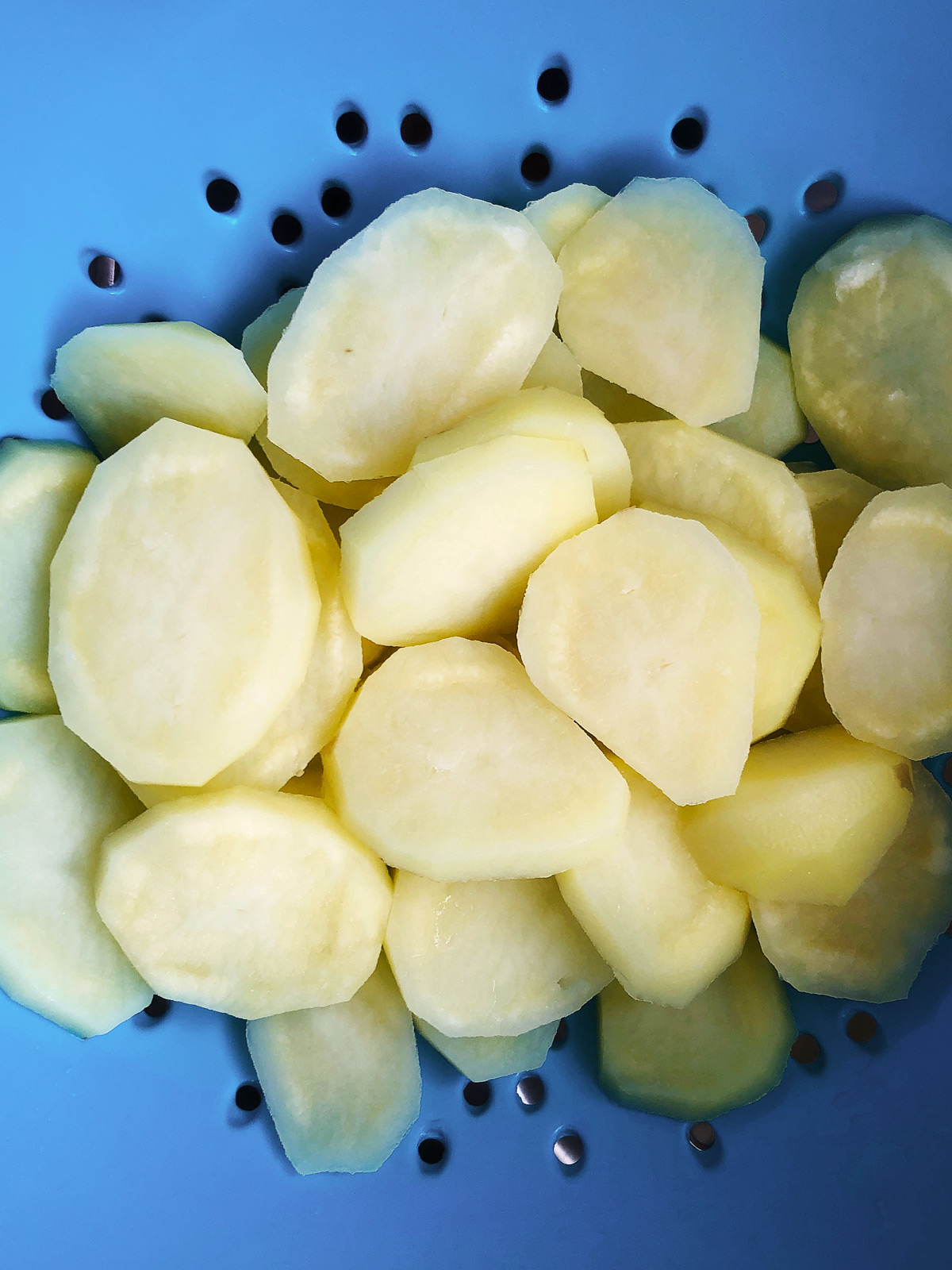 blanched potato slices in a colander