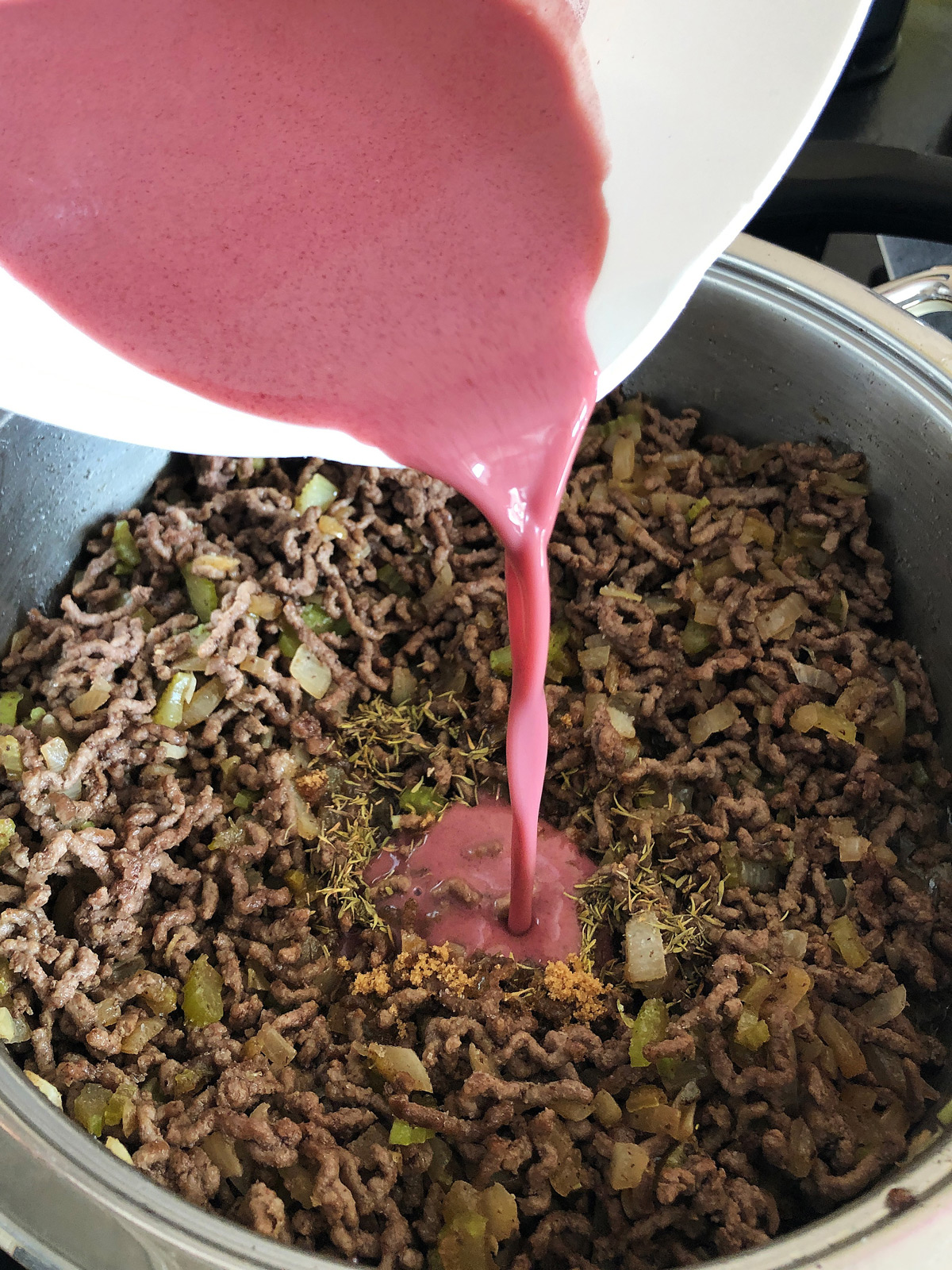 Pouring mixed red wine with flour into the browned beef mince