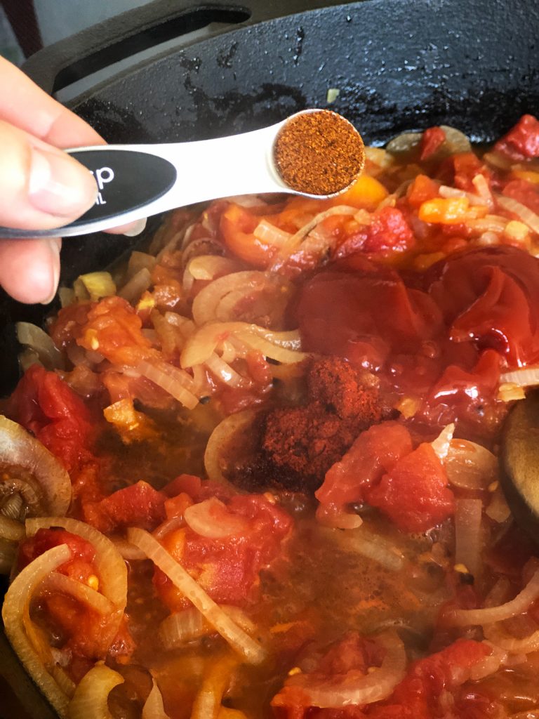 a hand adding spices to the casserole