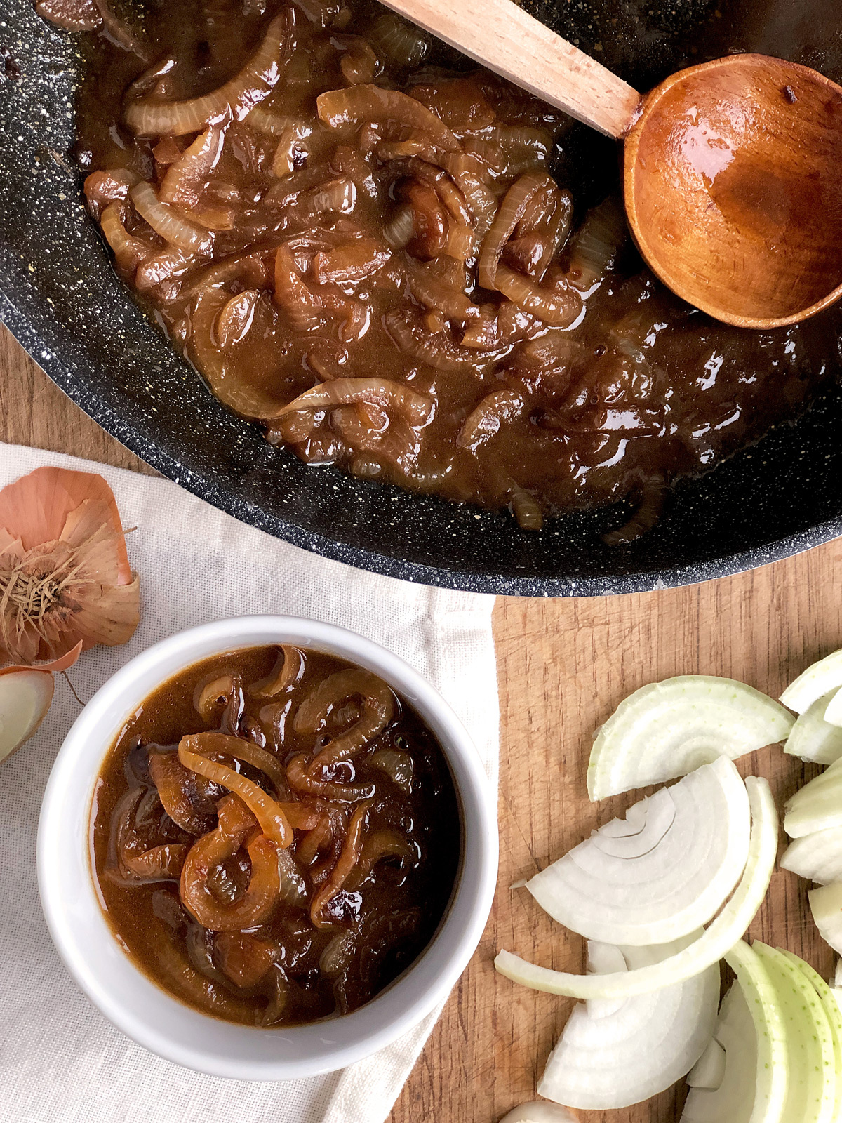 Caramelised onion gravy in a small white bowl ; sliced onion and non-stic pan with more gravy.