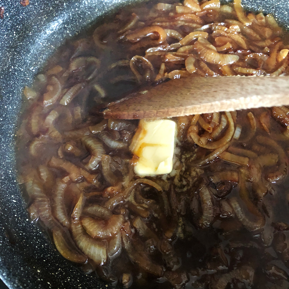 Melting a dollop of butter in onion gravy.