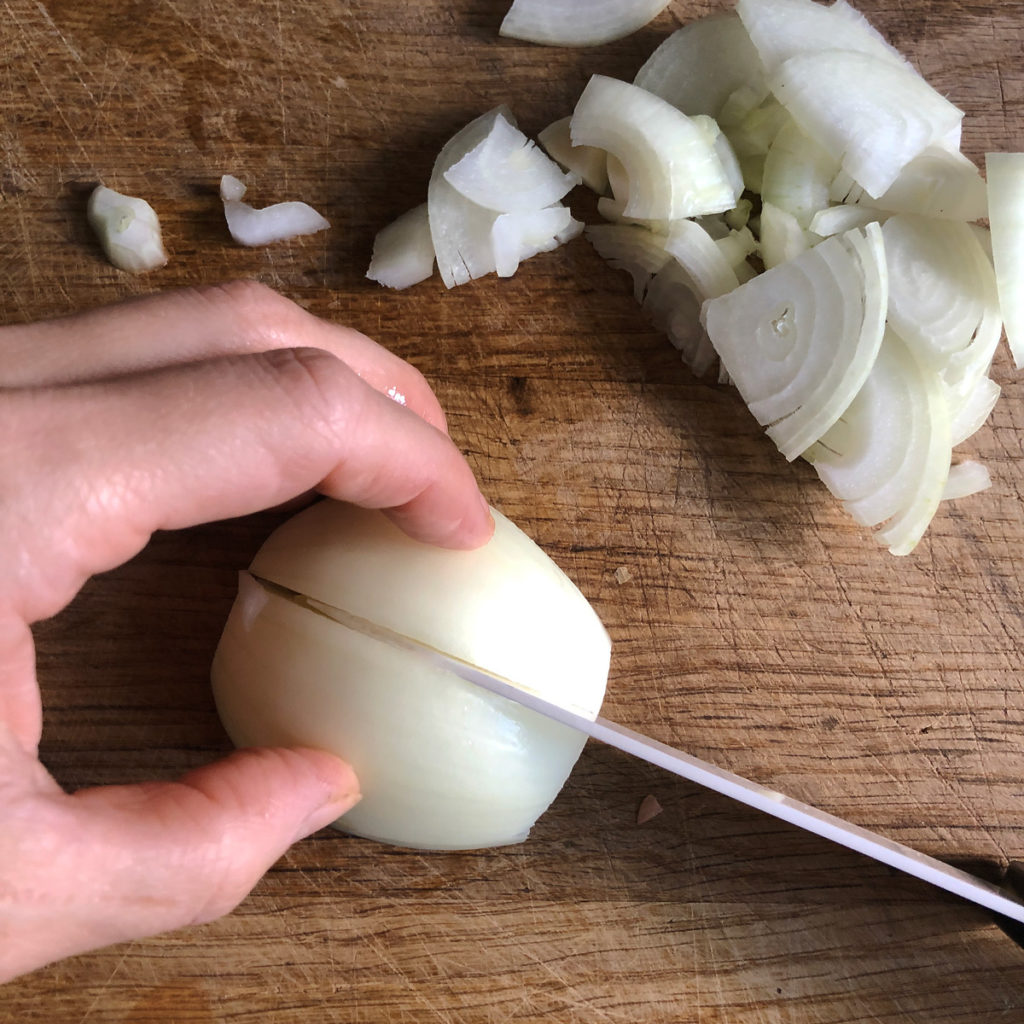 Chopping onion on a wooden chopping board.