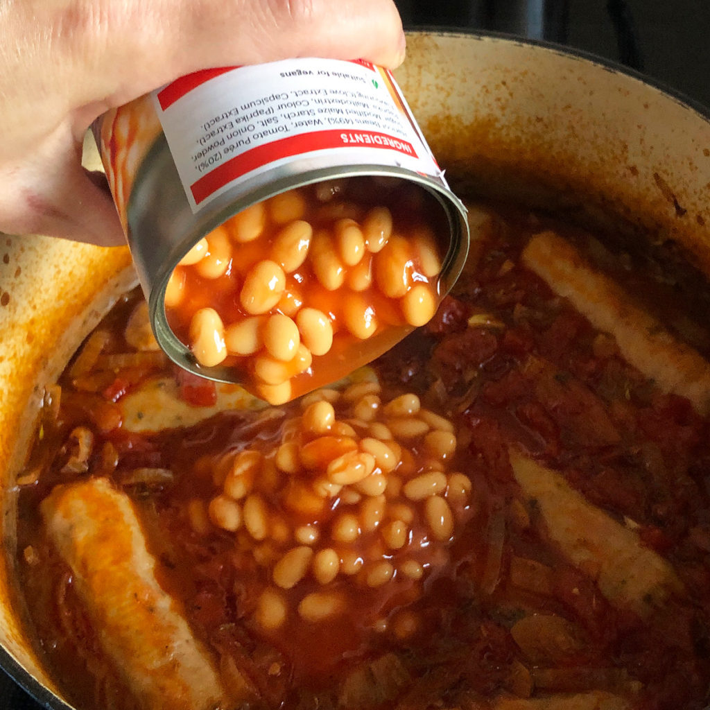 Adding baked beans into my sausage and bean hotpot.
