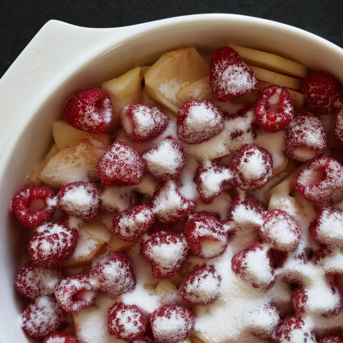 Sliced apples and fresh raspberries sprinkled with caster sugar.