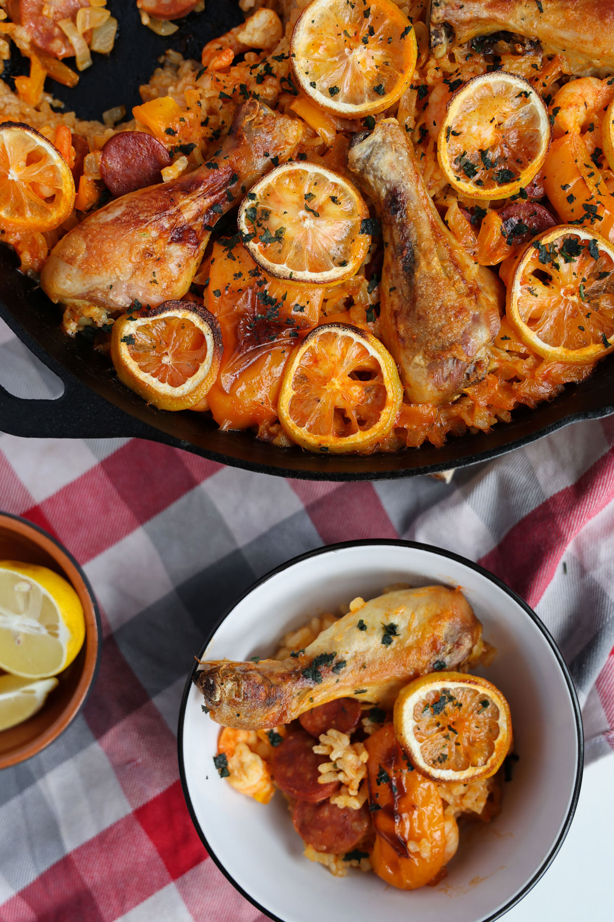 Bird-eye view - composition of a paella in a pan and a portion of paella with chicken in a bowl.