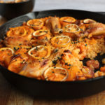 Paella with chicken chorizo and prawns in a cast-iron pan.