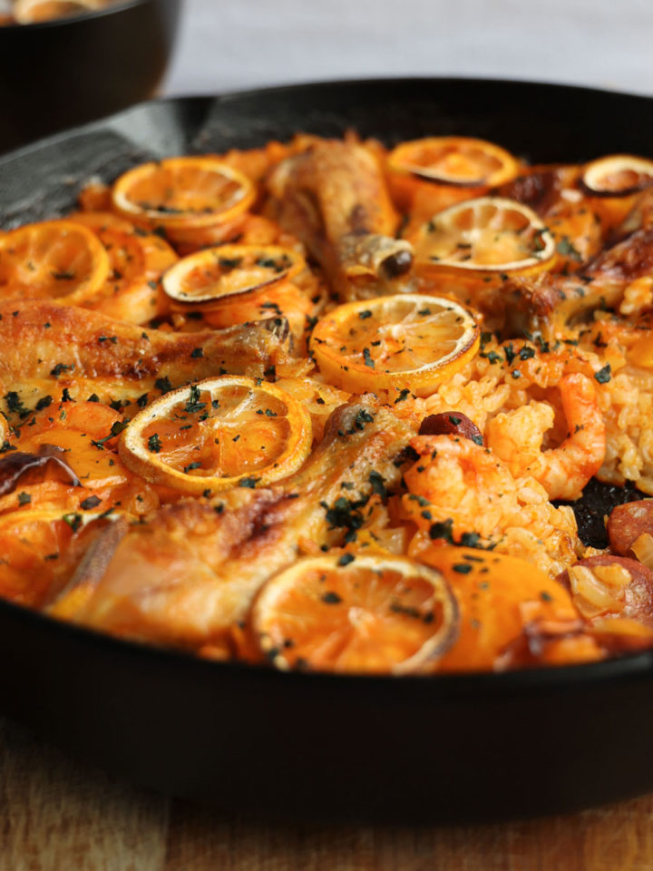 Paella with chicken chorizo and prawns in a cast-iron pan.