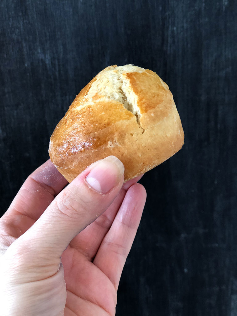 A hand holding a scone infront of black background.