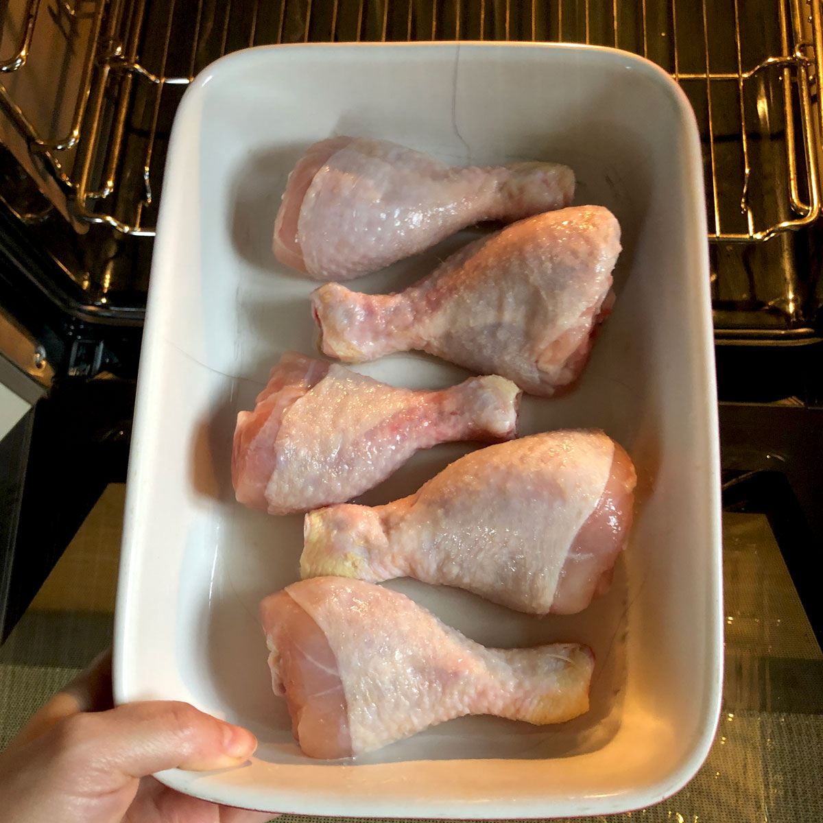 Picture of a recipe step - inserting chicken drumsticks into the oven.
