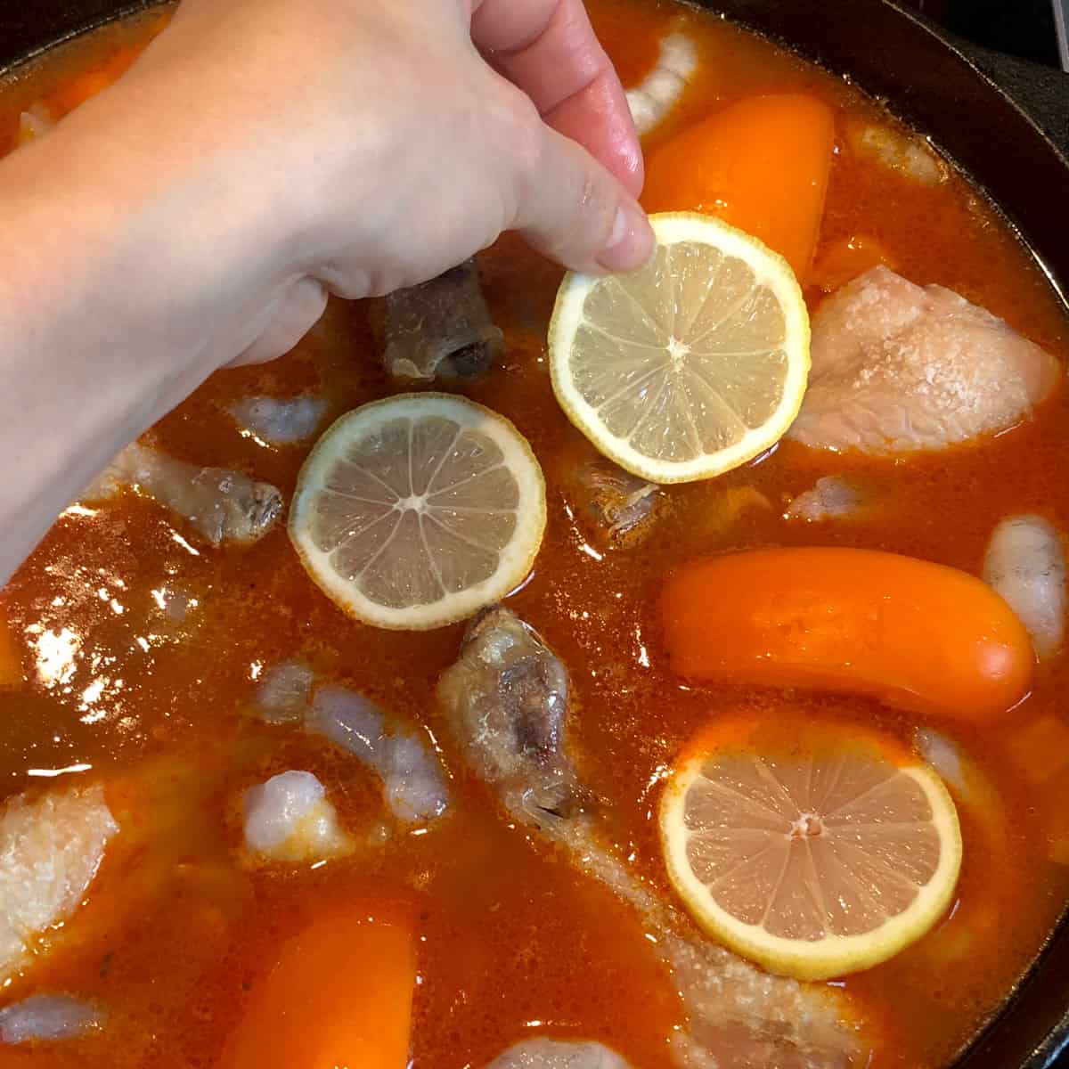 A picture of a recipe step - laying lemon slices on top of paella ingredients.