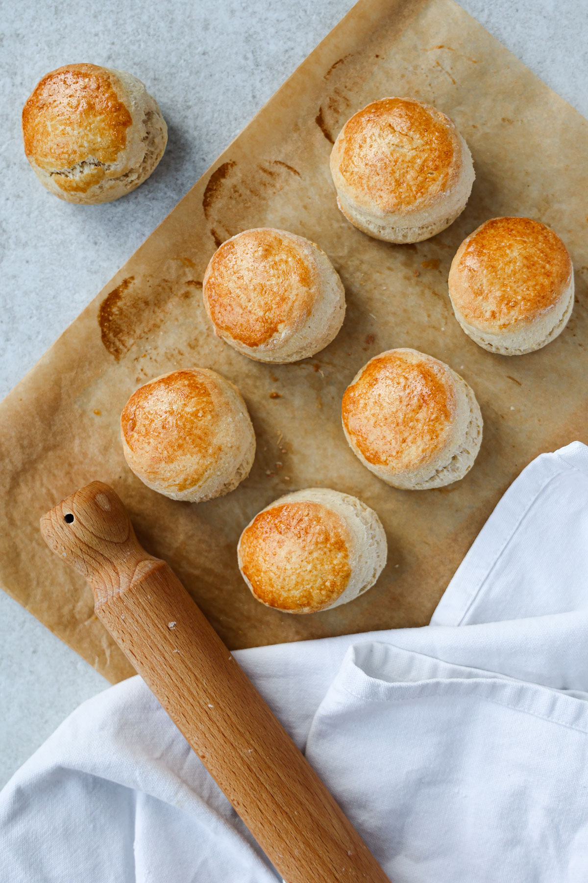 James Martin scones on baking paper with a wooden rolling pin next to them - bird-eye view.