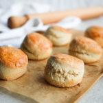 Six round scones on brown baking paper.