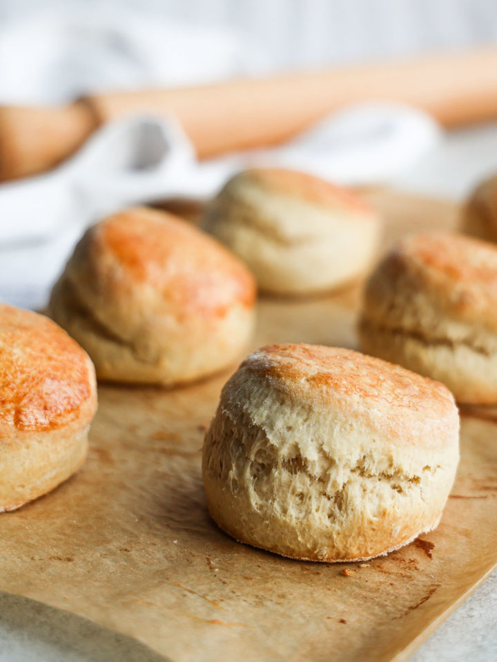 Six round scones on brown baking paper.