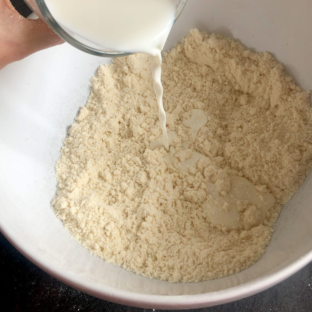 Pouring milk into flour.