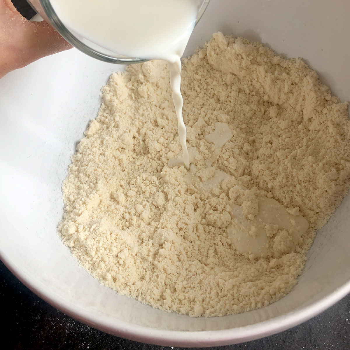 Pouring milk into flour.