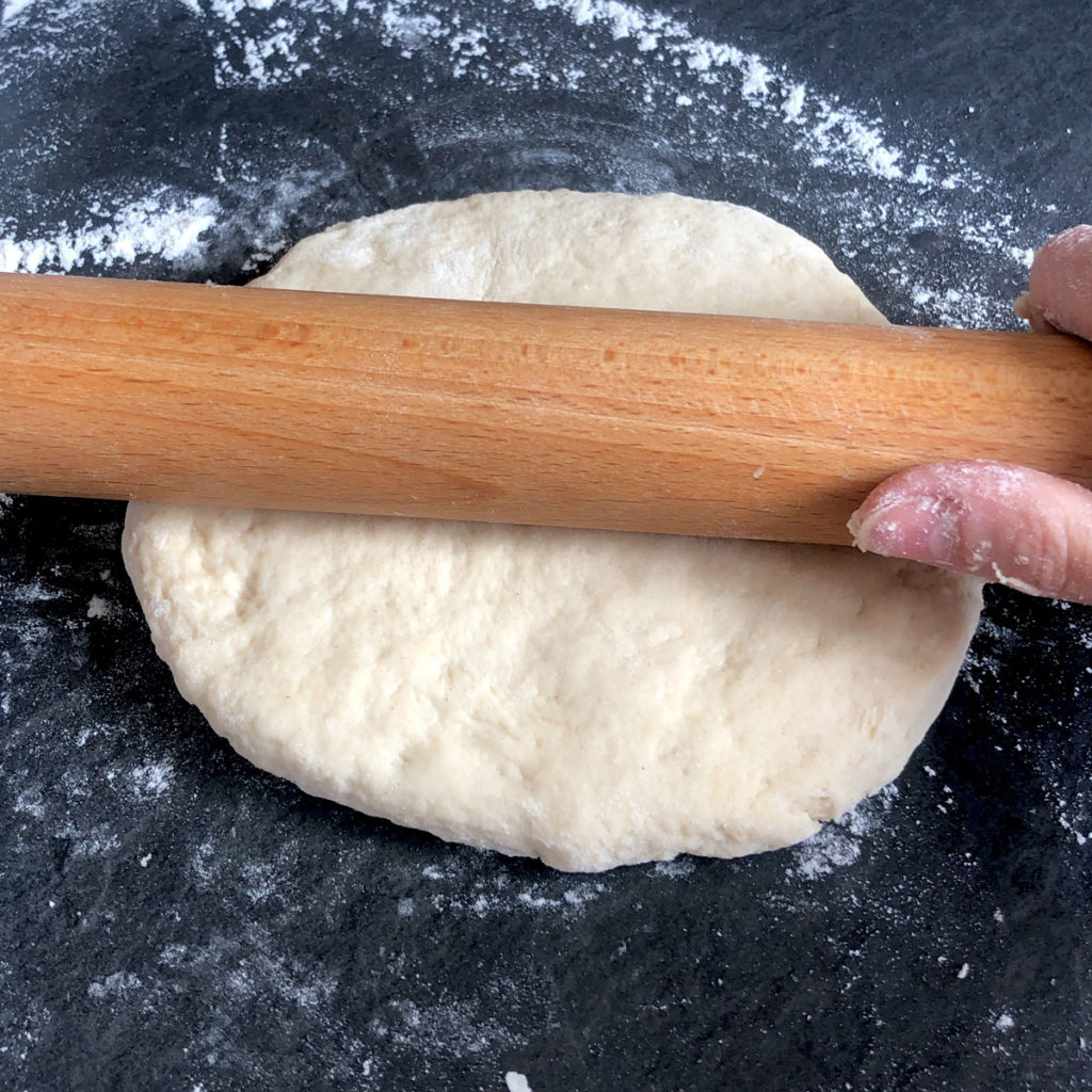 Flattening dough with a rolling pin.