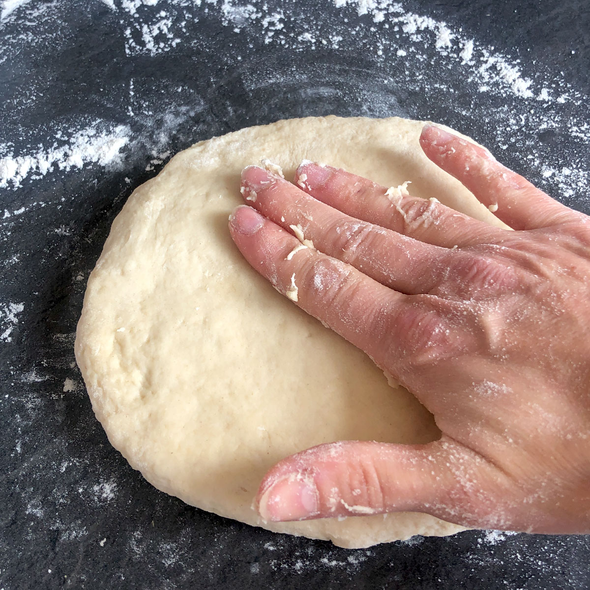 A hand patting the scone dough. 