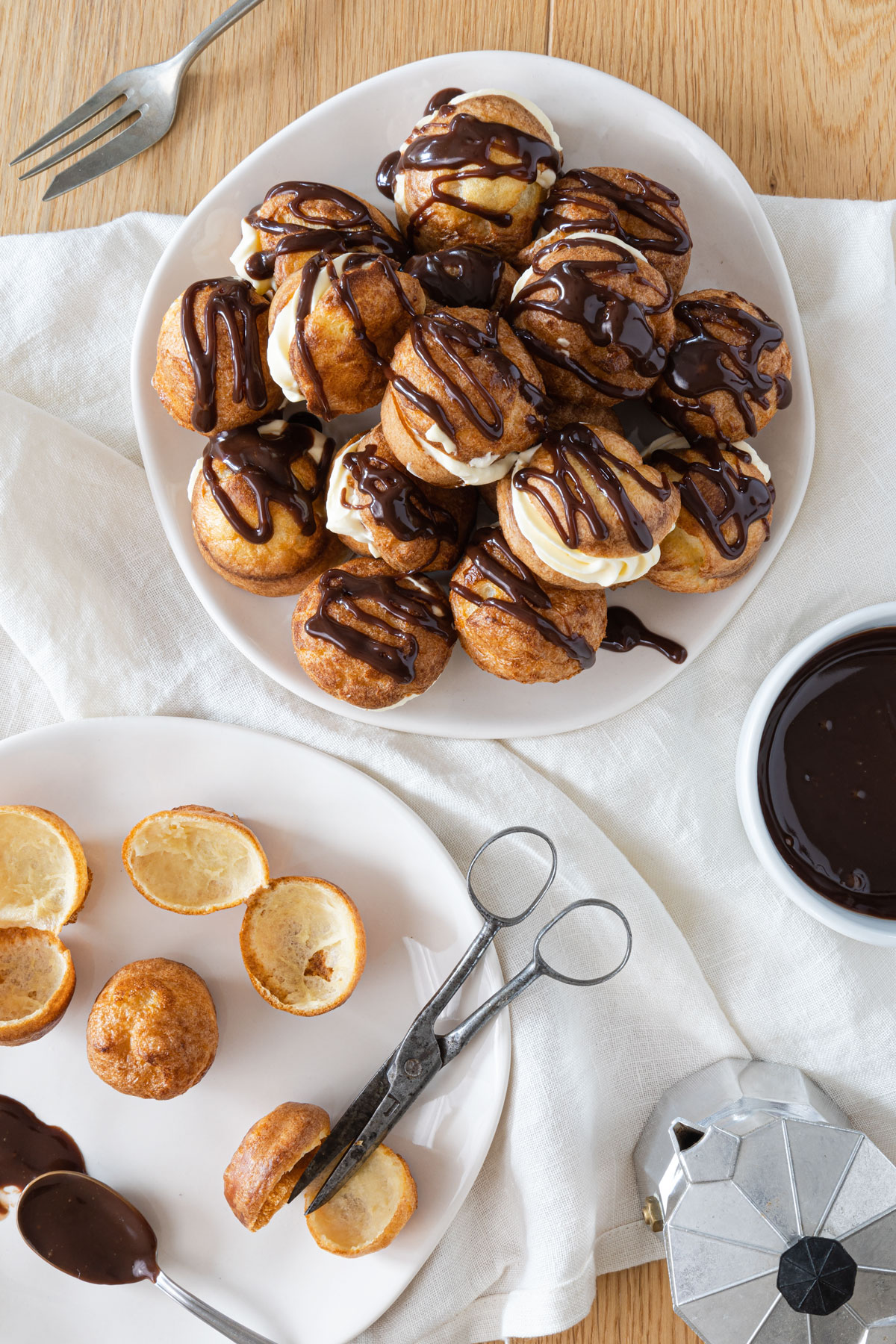 Yorkshire pudding decorated with cream and chocolate on a plate, scissors, old scissors and small cafetiere.