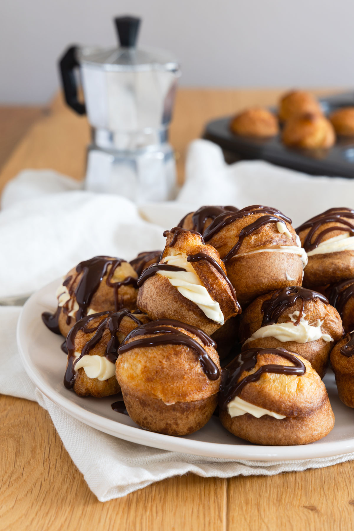 Mini Yorkshire Puddings decorated with cream and chocolate on a white plate.