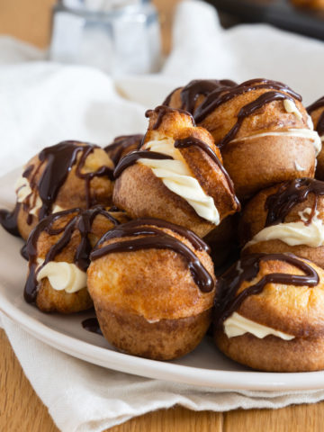Mini Yorkshire Puddings decorated with cream and chocolate on a white plate.