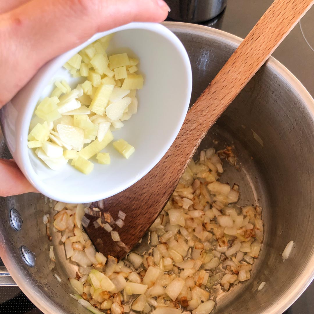 Adding chopped ginger and garlic to a pot with fried onion.