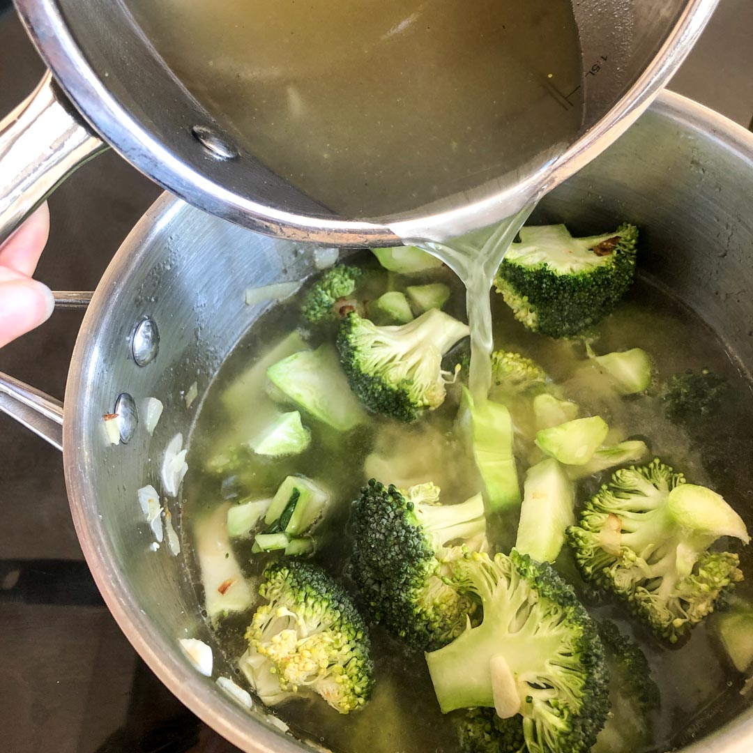 Adding vegetable stock to the broccoli soup.