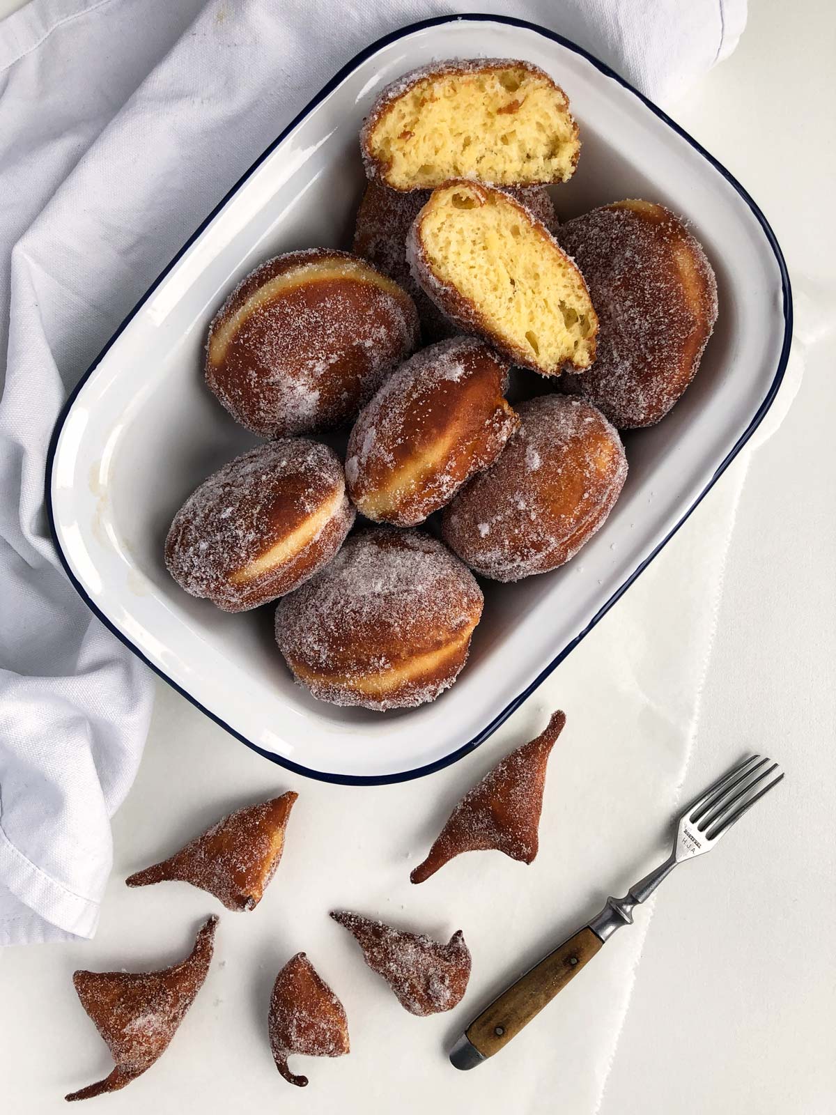 Lovely golden-brown doughnuts dusted with sugar in a white dish.