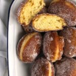 Close-up on golden brown doughnuts coated with caster sugar.