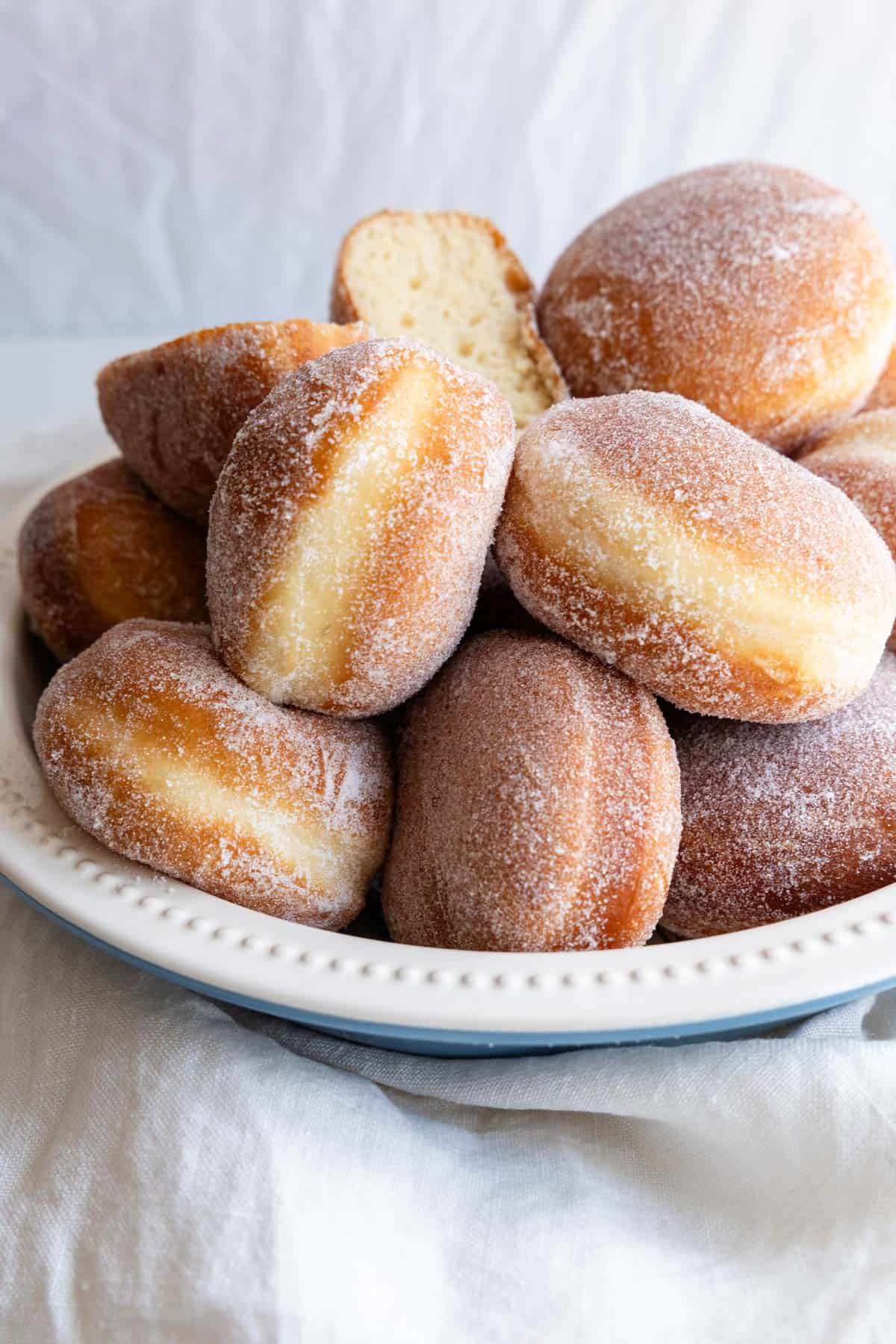 Golden-brown sugar coated doughnuts in a bowl.