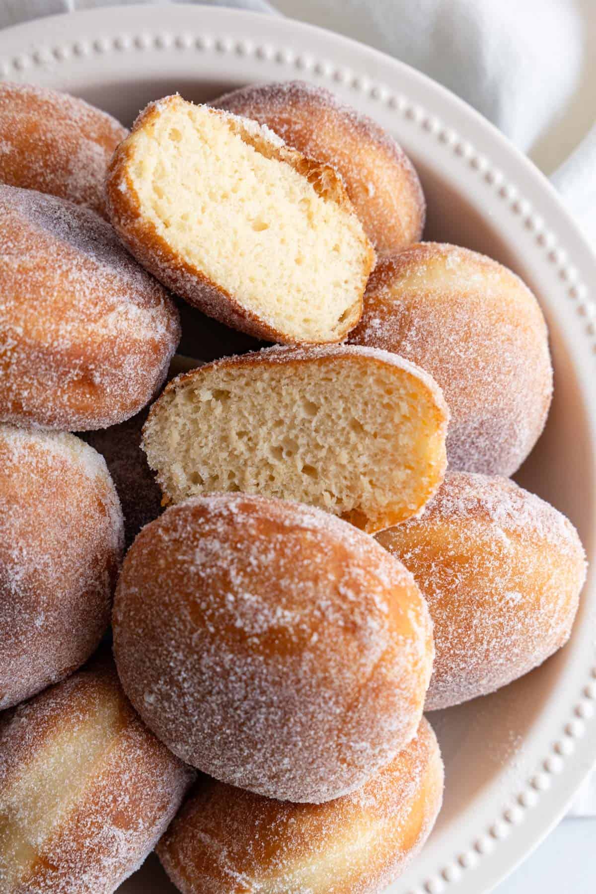 Doughnuts in a bowl; one doughnut cut in half.