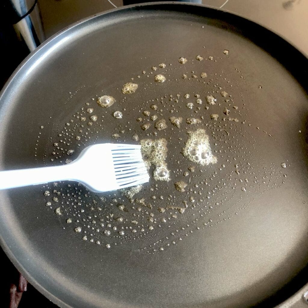 Greasing a hot pan with butter.