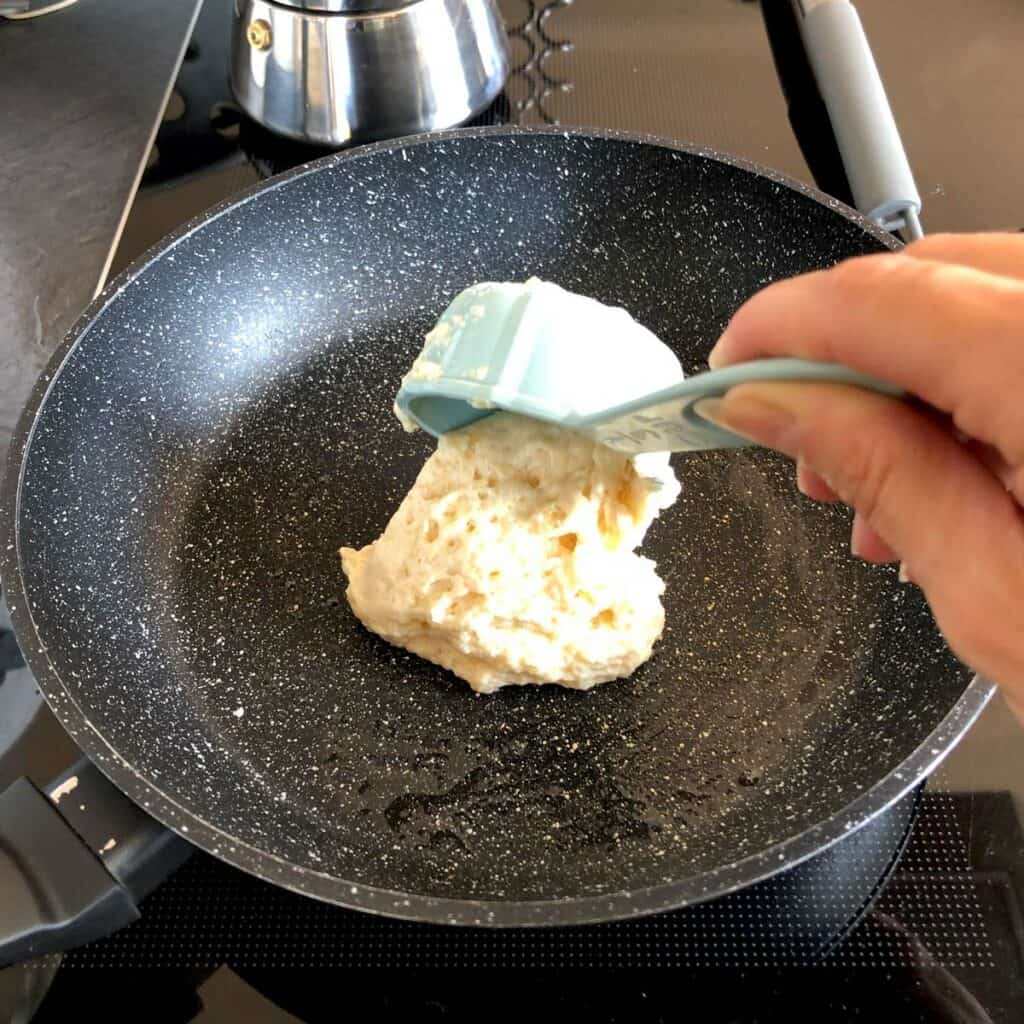 Scooping airy pancake batter onto a hot pan.